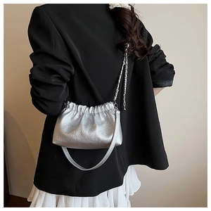 Détail du sac plissé argenté avec texture litchi et bandoulière en chaîne élégante