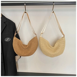 Detailed close-up of handmade straw woven half-moon bag texture and fabric shoulder strap