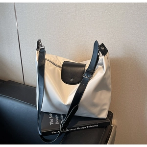 Close-up of white waterproof nylon tote bag with black leather straps on a sofa