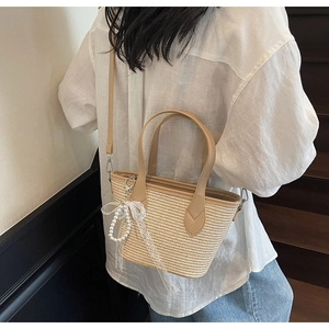 Détail du sac cabas en paille tressée avec bordure en cuir et nœud en dentelle perlé