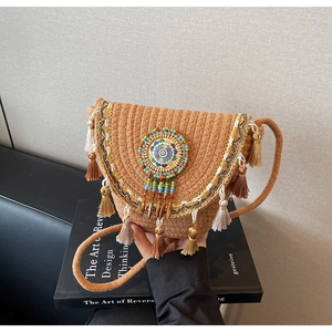 Detail of bohemian straw bag with beaded mandala, metallic charms and fringe trim