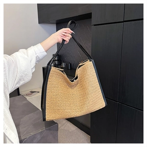 Détail du grand sac cabas en paille tissée avec bordure en cuir noir et bandoulières