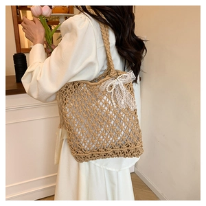Détail du sac bandoulière en paille tressée avec nœud en dentelle et pendentif perle