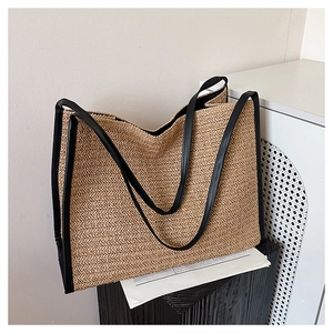 Détail d'un sac en paille avec lanières en cuir noir sur un support artistique