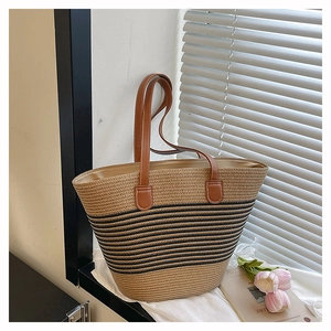 Détail d'un grand sac cabas en paille tissée à rayures noires et anses en cuir marron