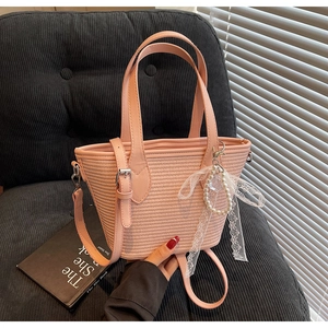 Détail du sac cabas rose tissé avec breloque nœud perle et bandoulière réglable