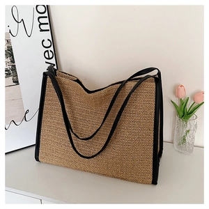 Détail du sac cabas en paille avec anses en cuir noir et texture tissée naturelle