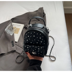 Detail of black quilted leather backpack with silver rhinestones and chain strap detail
