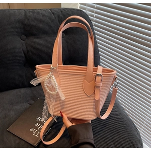 Détail du sac seau rose tressé avec pendentif en dentelle et perles et bandoulière