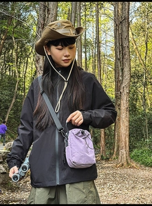 Outdoor view of a lightweight purple nylon drawstring crossbody bag with a hiking outfit