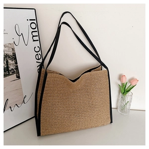 Détail du sac cabas en paille tissée avec bordure noire et ouverture en V