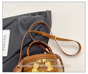 Close-up of brown bucket bag with gold bear hardware and printed silk scarf handle