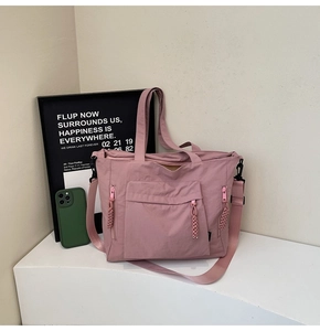 Detailed view of a pink nylon tote bag featuring a front flap pocket and adjustable straps