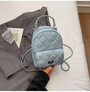 Macro view of blue denim mini backpack with quilted pattern and sparkling rhinestones