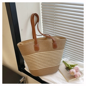 Détail du sac cabas tissé avec poignées en cuir marron et finitions de coutures blanches