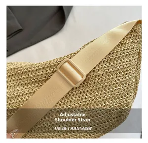 Detail of adjustable woven shoulder strap with plastic buckle on a beige straw beach bag