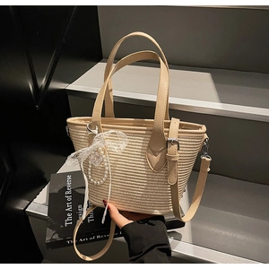 Détail d'un sac en paille tressée avec anses en cuir, nœud en dentelle et perles