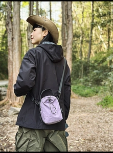 Detail of purple nylon drawstring crossbody bag with Smile logo tag in outdoor forest setting
