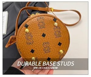 Detail shot of golden metal bottom studs and brown lychee grain leather on crossbody bag