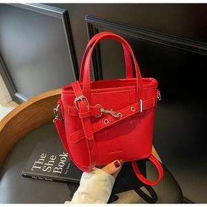 Dettaglio della borsa a secchiello in pelle rossa con cinturini e fibbia in metallo