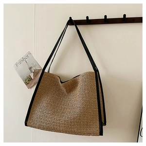 Détail du cabas en paille tissé main avec bordure en cuir noir sur crochet en bois