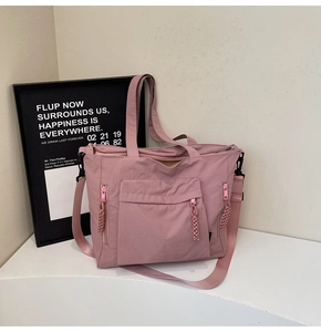 Detail view of pink nylon tote bag with functional pockets and woven knot zipper pullers