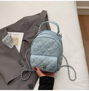 Detail of light blue denim quilted mini backpack with rhinestones and chain strap