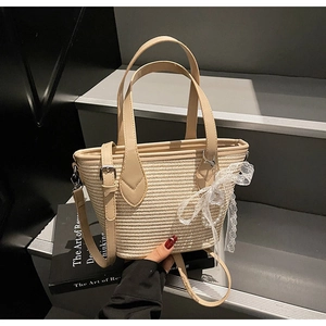 Détail du sac en paille tressée avec nœud en dentelle blanche et pendentif perle