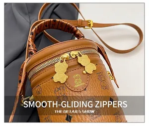 Macro view of brown leather bucket bag with bear print and silk scarf handle detail
