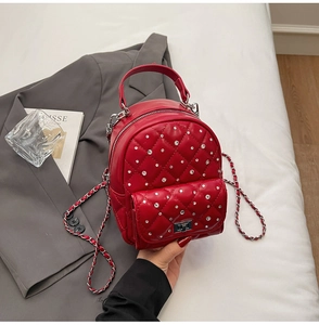 Detail of red quilted mini backpack with rhinestone embellishments and silver chain