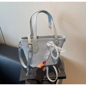 Détail du sac cabas tissé avec bandoulière en cuir bleu clair et nœud en dentelle perlé