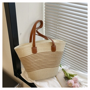 Détail de la texture d'un sac cabas en paille avec poignées en cuir et rayures dégradées