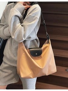 Large khaki nylon tote bag with leather flap shown on model in a casual lifestyle setting