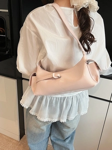 Pink glossy leather shoulder bag featuring a sleek dumpling shape and wide strap