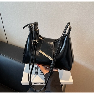 Detail der glänzenden schwarzen Lackledertasche mit silbernem Metallstab und Riemen