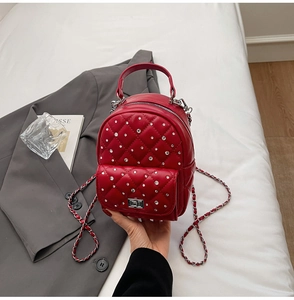 Detail of red quilted mini backpack with sparkling rhinestones and silver chain strap