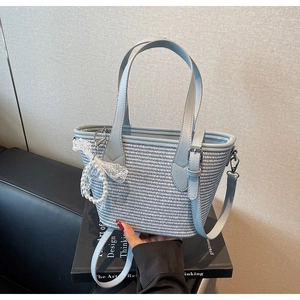 Détail d'un sac cabas tissé bleu clair avec breloque en dentelle de perles et bandoulière
