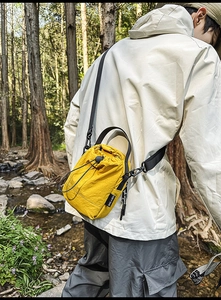 Detail of a bright yellow drawstring crossbody bag with durable black shoulder strap