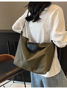 Military green nylon tote bag with black leather flap and adjustable shoulder strap