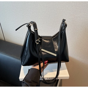 Detail einer schwarzen Lackleder-Schultertasche mit silberner Metallschnalle und Glanz-Finish