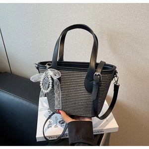 Détail d'un sac en paille tressée avec nœud en dentelle perlée et anses en cuir
