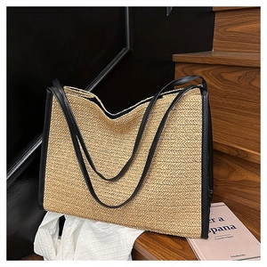 Détail du sac cabas en paille tissée avec anses en cuir noir sur des marches