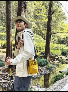 Outdoor close-up of a bright yellow drawstring crossbody bag with a trekking pole detail