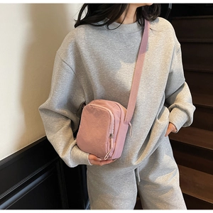 Rosafarbene Nylon-Handytasche an einem Model mit grauem Freizeitoutfit im Treppenhaus