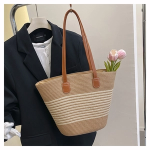 Détail du sac cabas en paille tissée avec poignées en cuir marron et rayures
