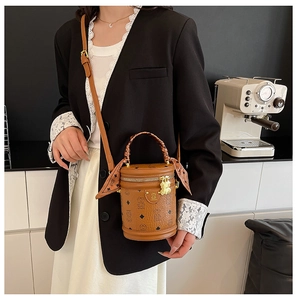 Chic brown bucket bag with bear monogram and decorative silk scarf shown in lifestyle setting