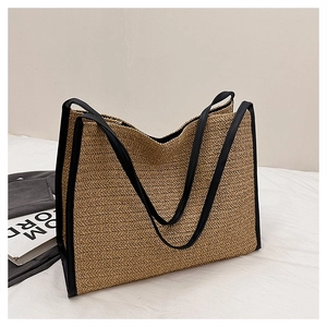 Gros plan du sac cabas en paille avec bordure en cuir noir sur un drap blanc