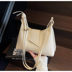 Detail der cremefarbenen minimalistischen Beuteltasche mit goldenen Schnallen auf Holz