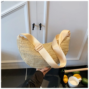 Detail of hand-woven beige crescent bag with a wide adjustable cream shoulder strap