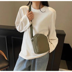 Olivgrüne Crossbody-Handytasche mit verstellbarem Riemen am Modell in lässiger Umgebung
